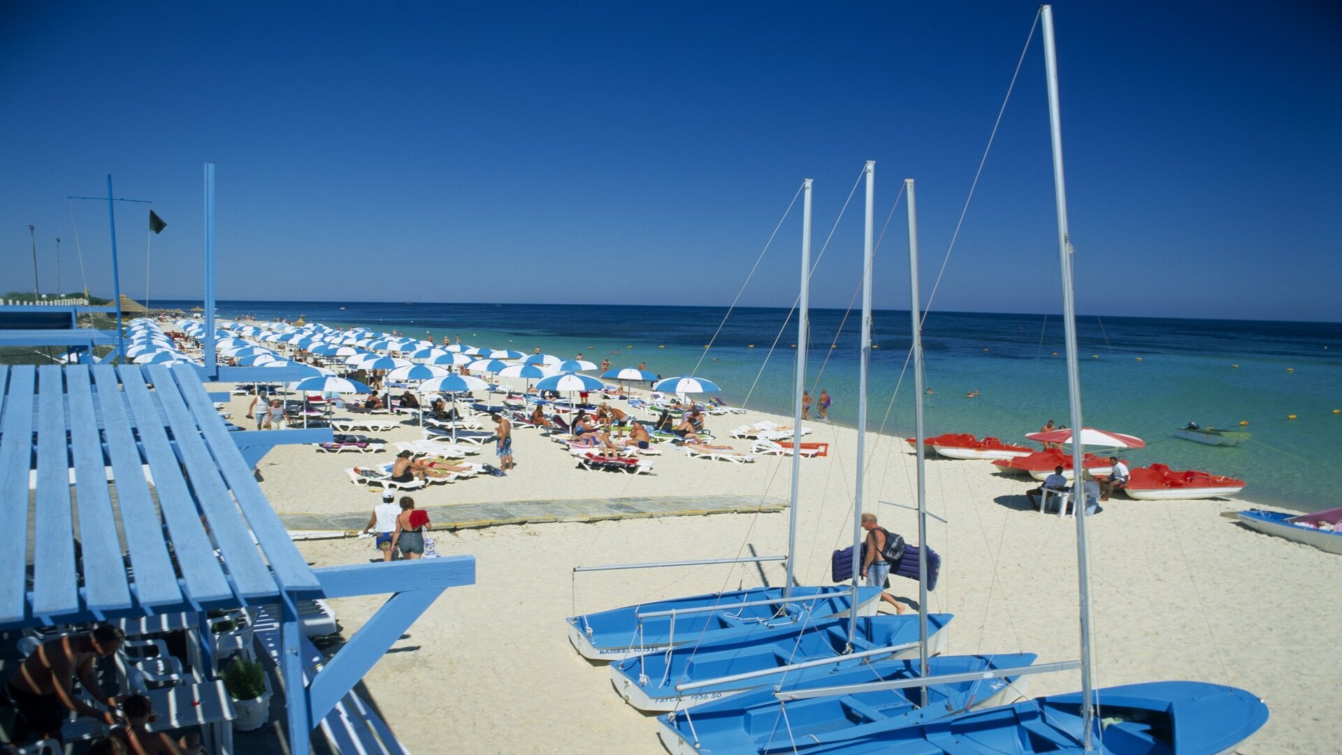 Оживленный песчаный пляж с туристическими лодками, Порт-эль-Кантауи, Тунис.